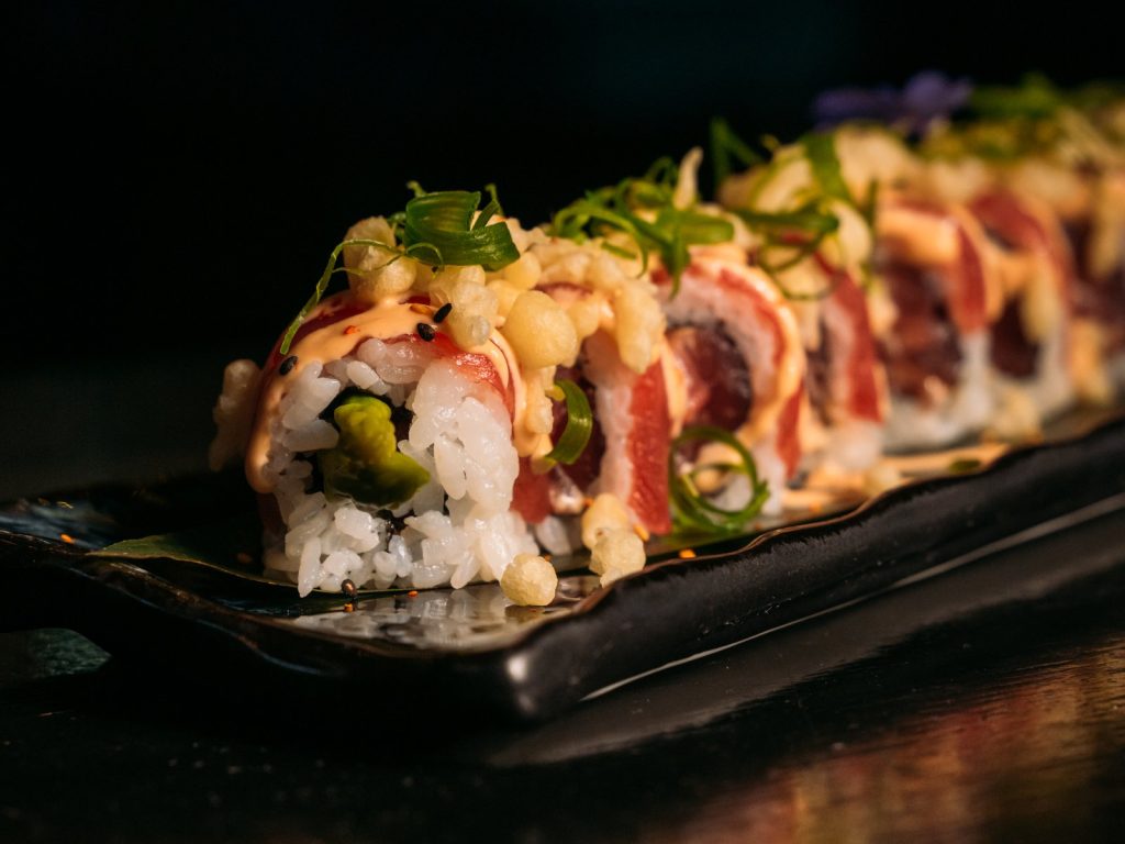 Sushiroll met verse vis, lente-ui en crunch op een zwarte plank bij Brasserie Pastis in Rosmalen