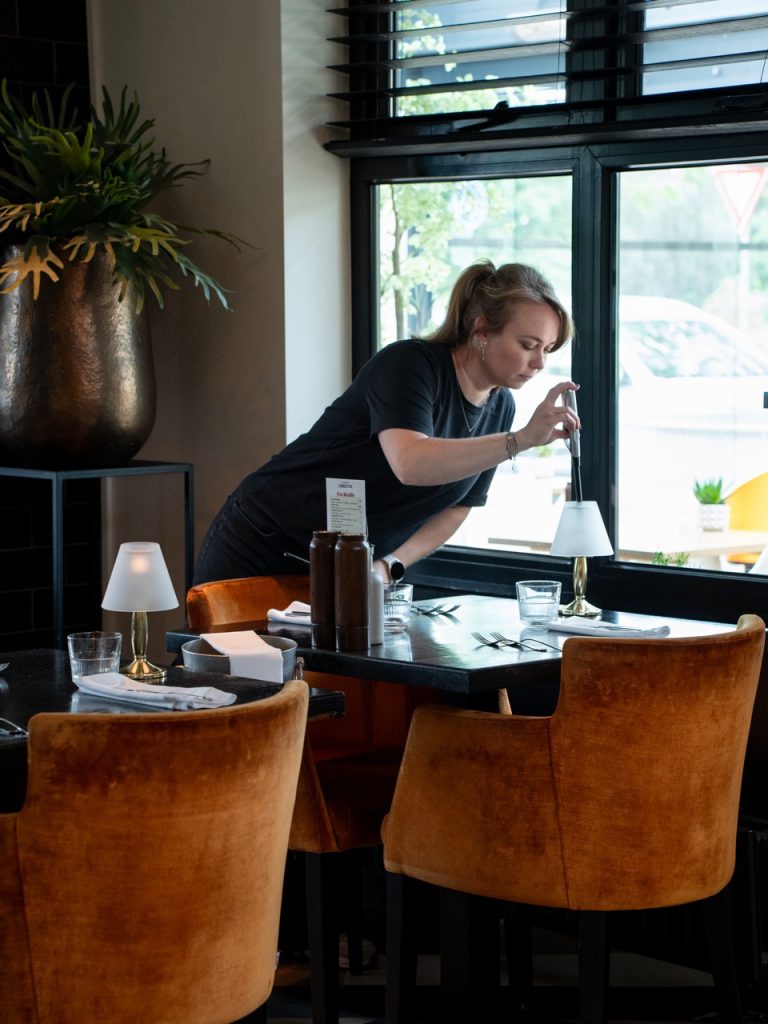 Medewerker van de bediening zet een tafel in het restaurant van Brasserie Pastis