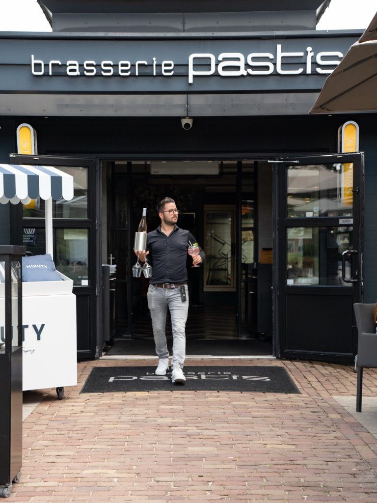 Medewerker van Brasserie Pastis komt met flessen naar buiten bij de ingang in Rosmalen