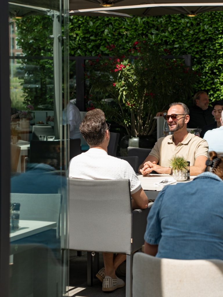 Gasten lachend aan tafel op het terras van Brasserie Pastis