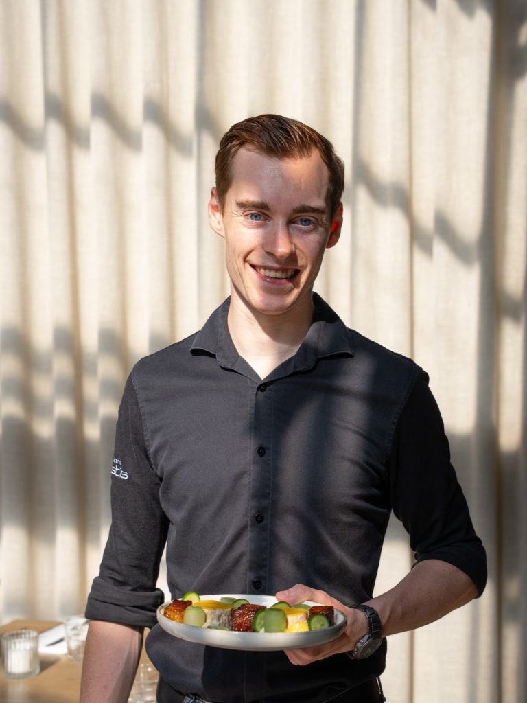 Medewerker van Brasserie Pastis brengt een bord naar tafel
