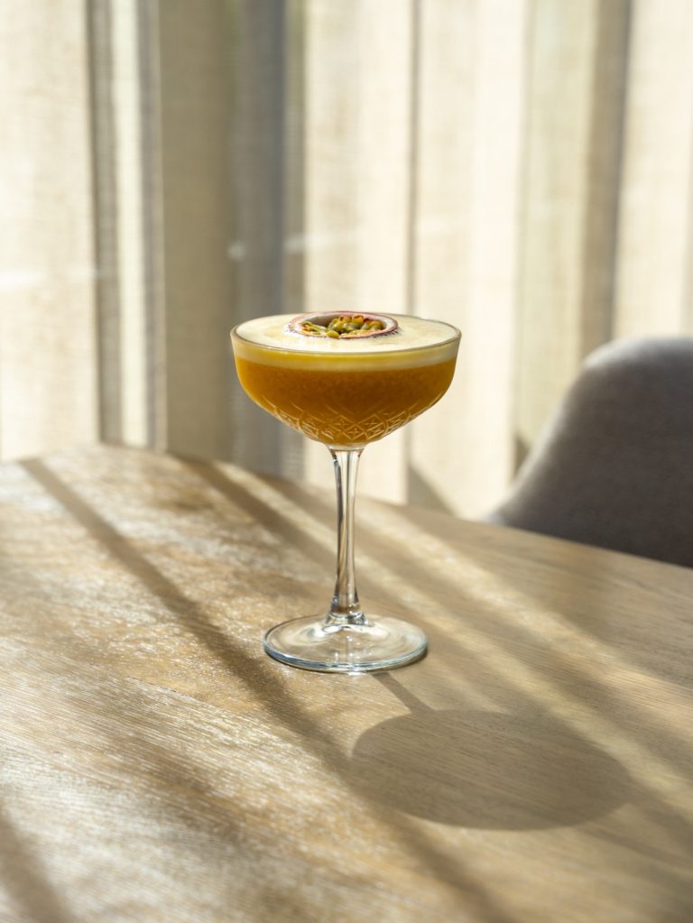 Cocktail in een coupeglas met strijklicht op een houten tafel