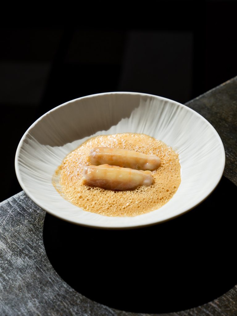 Dessert met krokante rolletjes en gemalen noten op een wit bord