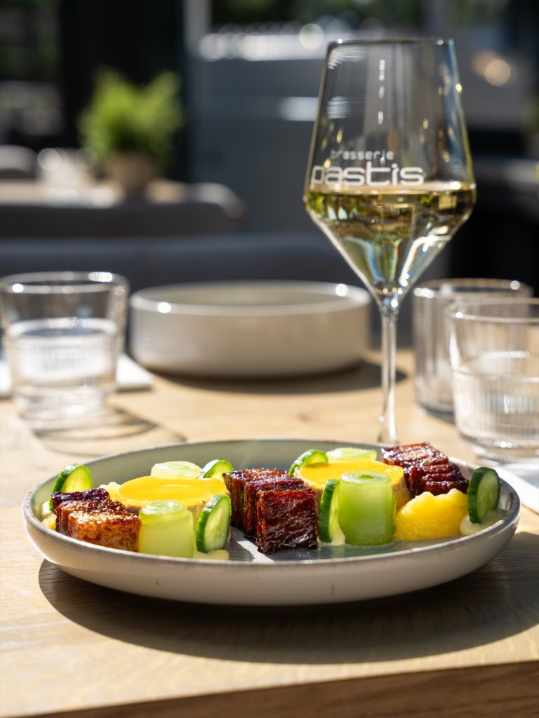 Gedekte tafel met wijnglas en een gerecht van gelakt buikspek in het restaurant