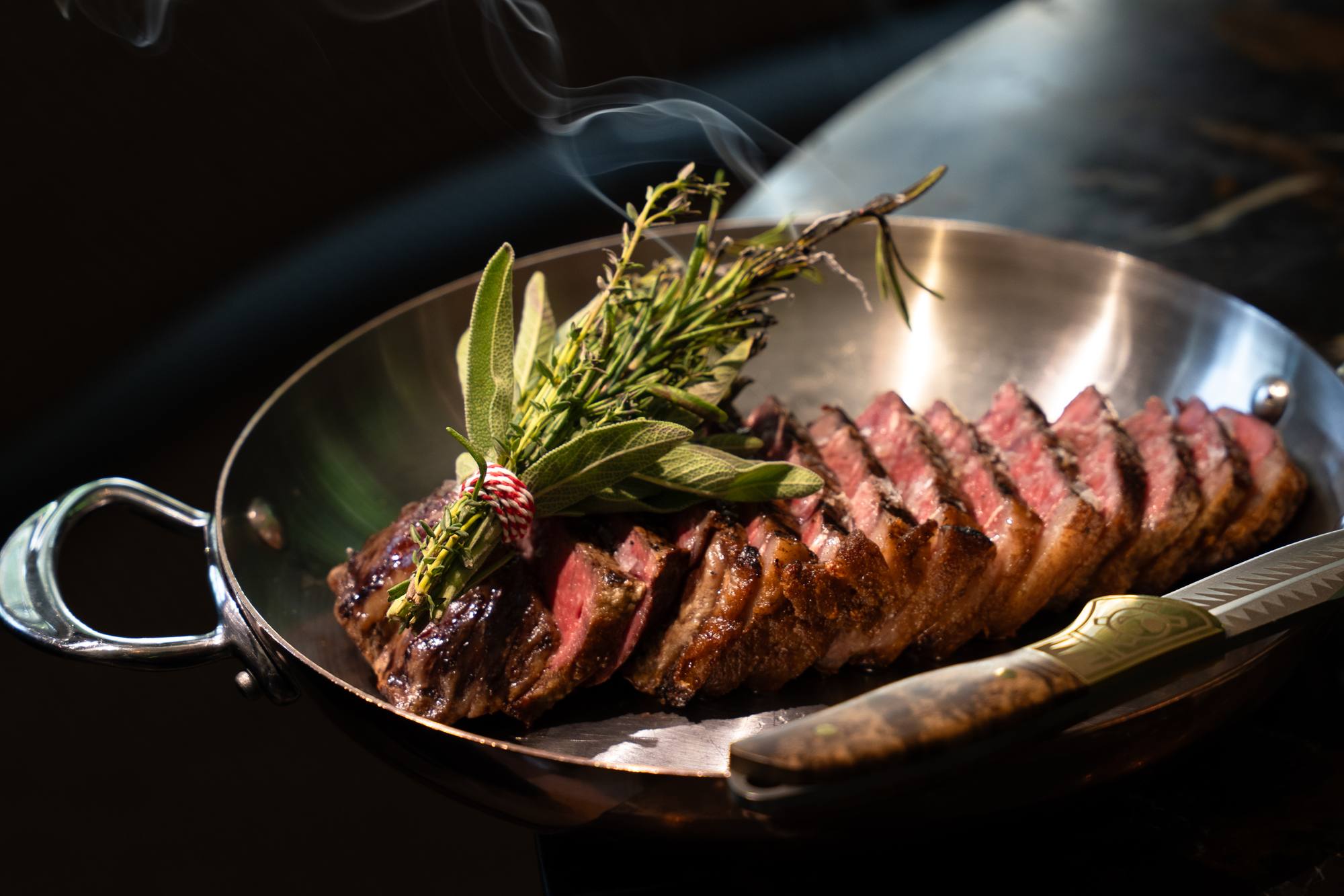 Aangesneden steak met verse kruiden in een koperen pan bij Brasserie Pastis