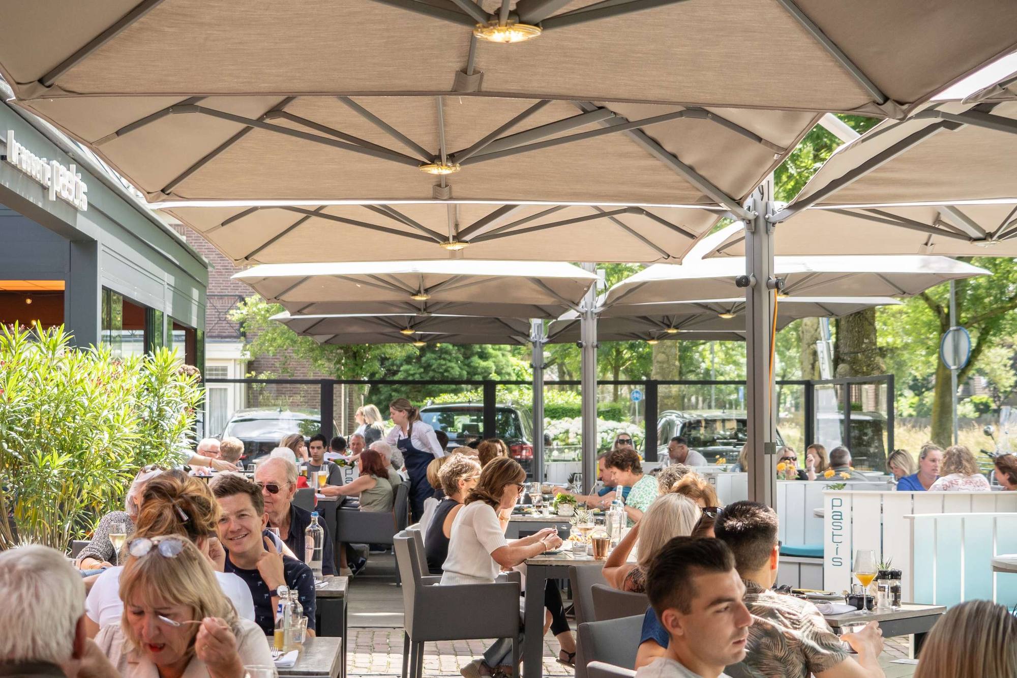 Het volle terras van Brasserie Pastis in Rosmalen onder de parasols